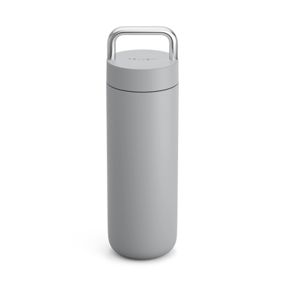 The Fellow Carter Carry Travel Mug is a sleek gray insulated mug with a silver top handle.