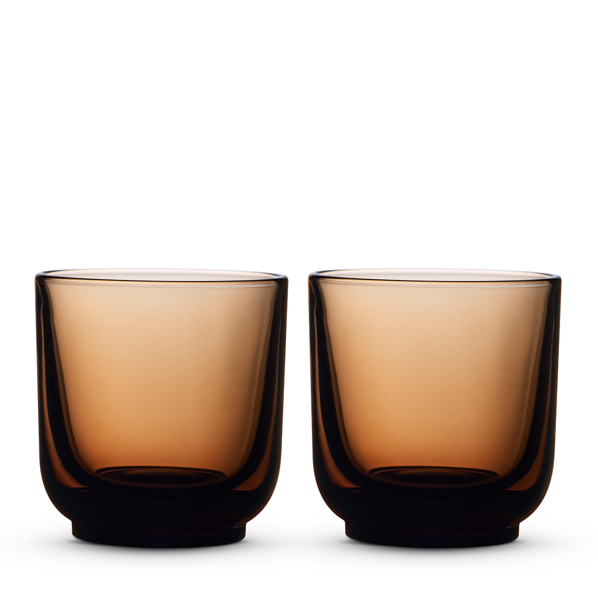 Two amber Pirch Espresso Glasses by Fellow sit side by side on a white background.