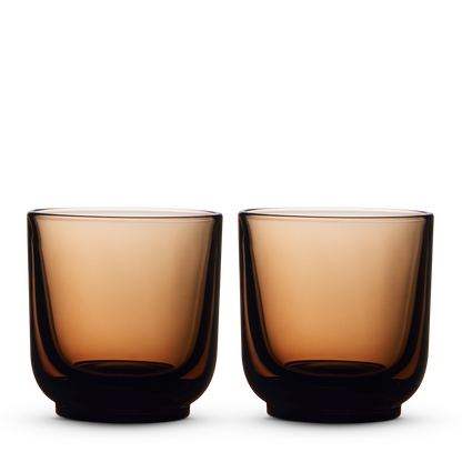 Two amber Pirch Espresso Glasses by Fellow sit side by side on a white background.