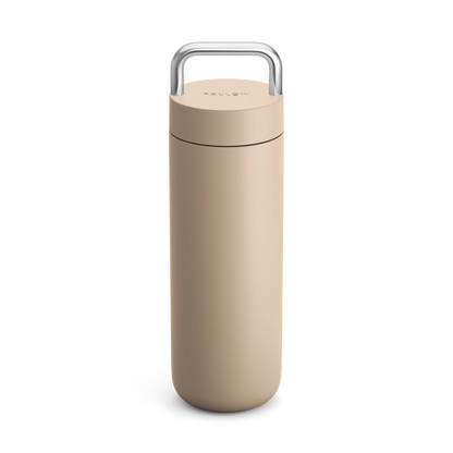 Fellow Carter Carry Travel Mug in beige with silver handle on a white background.