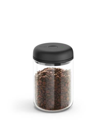 Fellow Atmos Vacuum Canister with black lid, filled with coffee beans on a white background.