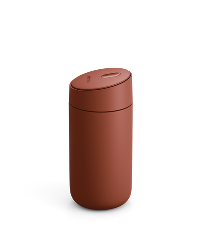 A matte rust-red Carter Slide Mug by Fellow with a rounded lid on a white background.
