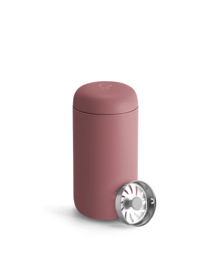 A pink Fellow Carter Move Mug with metal infuser lid sits beside it.