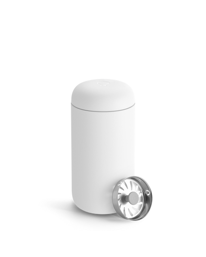 A Fellow Carter Move Mug with a metal lid sits beside it on a plain background.