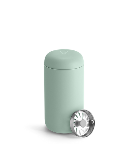 Light green Fellow Carter Move Mug with removable silver lid placed beside it.
