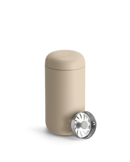 Beige Fellow Carter Move Mug with removable metal infuser lid placed beside it.