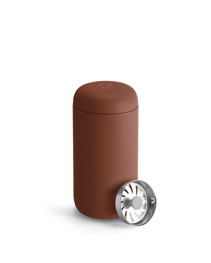 Fellow Carter Move Mug with lid next to a metal part with radial openings.
