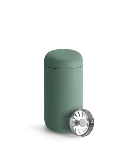 Matte green Fellow Carter Move Mug with lid and metal strainer in front.