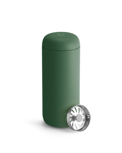 A matte green Fellow Carter Move Mug with a metal strainer leaning against it.