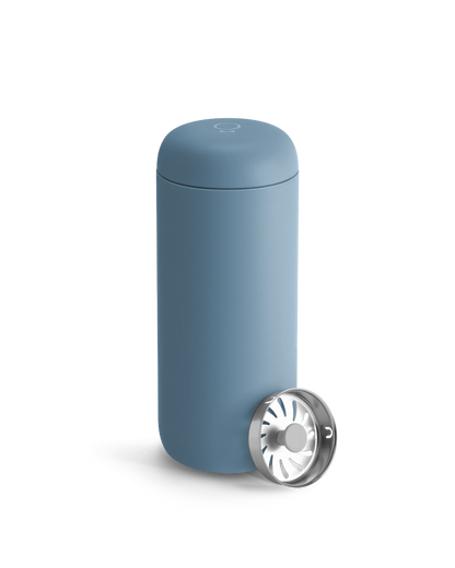 A Fellow Carter Move Mug in blue sits beside its metal strainer on a white background.