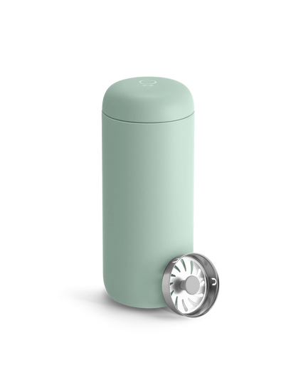 Fellow Carter Move Mug in light green with stainless steel strainer on a white background.
