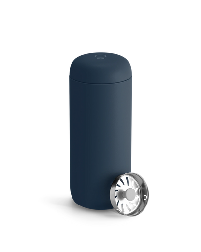 A Fellow Carter Move Mug in navy blue with its lid off and set next to it.
