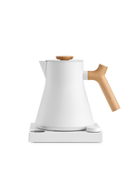 Fellow Corvo EKG Electric Kettle with wooden handle on a sleek white base.