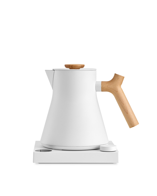 Fellow Corvo EKG Electric Kettle with wooden handle on a sleek white base.