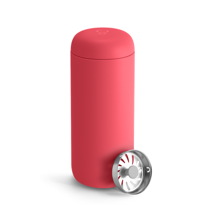 A Coral Crush Fellow Carter Move Mug with a removable metal filter cap placed beside it.